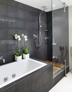 a bathroom with a bathtub, shower and flowers in vases on the counter