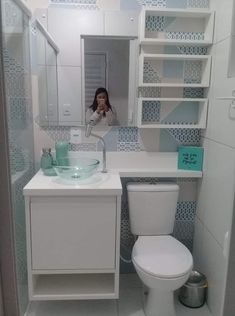 a woman taking a selfie in the mirror of a bathroom with blue and white tiles on the walls