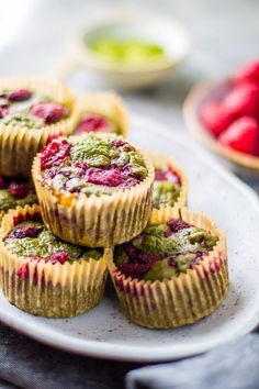 several small cupcakes on a plate with raspberries and guacamole in the background