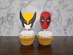 two cupcakes with masks on top of them