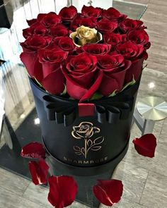 a black box filled with red roses on top of a table