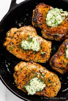 four pieces of chicken in a skillet with parmesan cheese and herbs on top