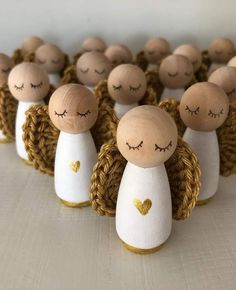 small wooden angel figurines lined up in a row with eyes closed and hearts drawn on them