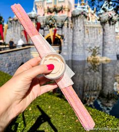 a person holding up a pink tube in front of a castle