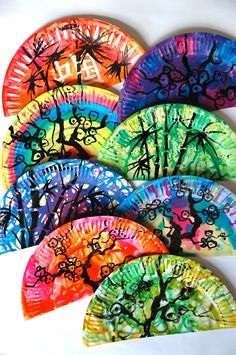 four colorful paper plates with trees painted on the sides and numbers written in different colors