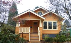 a small yellow house with stairs leading up to the front door