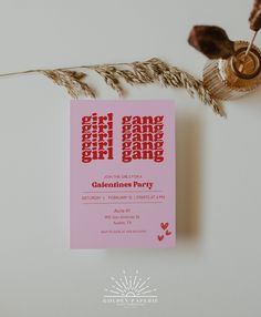 a pink business card sitting on top of a table next to dried plants and a plant