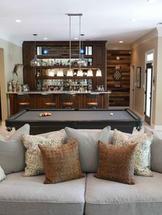 a pool table in the middle of a living room with couches and pillows on it