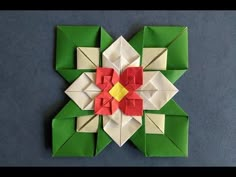 an origami flower with red, yellow and green flowers on it's petals