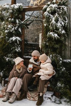 three people sitting on a bench in the snow