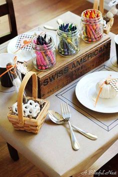 a table topped with lots of different colored crayons and cupcakes on top of a wooden box