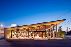 an empty parking lot next to a building with glass walls and doors on the front