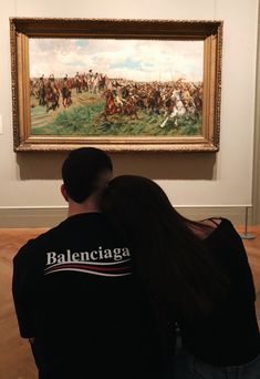 a man and woman sitting in front of a painting with horses on it's back