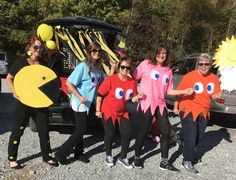 some people are standing in front of a car wearing costumes that look like fish and sun