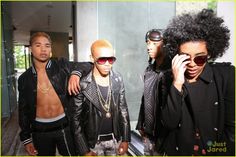 the group of young men are posing together in front of a building with sunglasses on