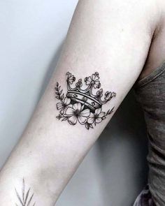 a woman's arm with a crown and flowers tattoo on the left side of her arm