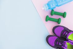 a pair of purple shoes next to two green dumbs and a blue water bottle