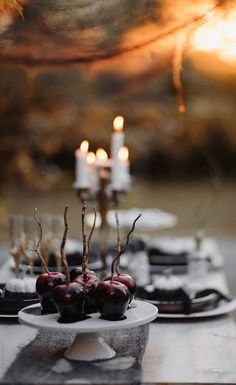 some apples are sitting on a white plate with candles in the background and an image of trees behind them