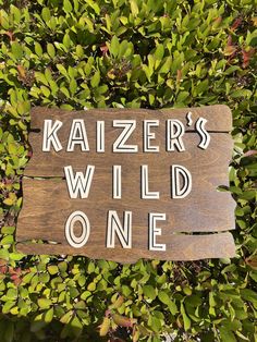 a wooden sign that says kaiserer's wild one on top of some bushes