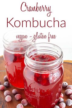 two jars filled with cranberry kombucha on top of a wooden table