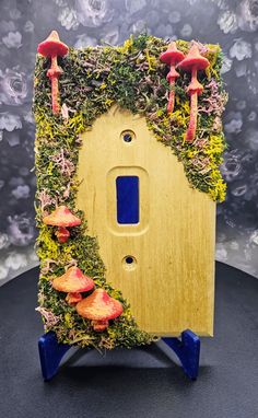 a light switch cover covered in moss and mushrooms