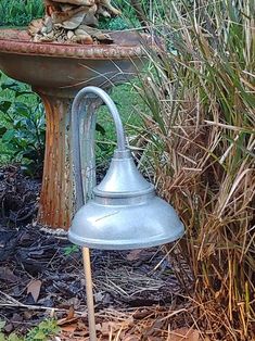 an old fashioned sink in the middle of some grass and weeds with a statue on top