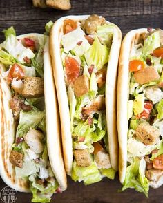 three tacos with lettuce, tomatoes and chicken on them next to chips