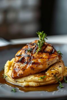 grilled chicken and potatoes on a plate with garnishes in the foreground