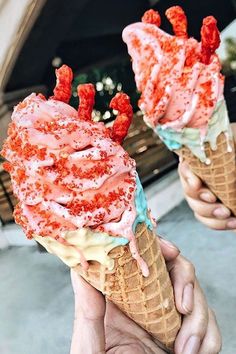 two people holding up ice cream cones with red and blue sprinkles on them