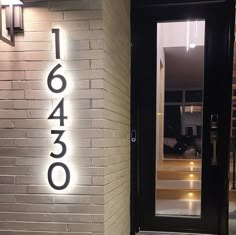 the front door of a building with a lit up address sign on it's side