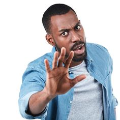 a man making a hand gesture with his right hand while wearing a blue shirt and gray t - shirt