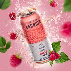 a pink background with raspberries and water splashing on top of the can