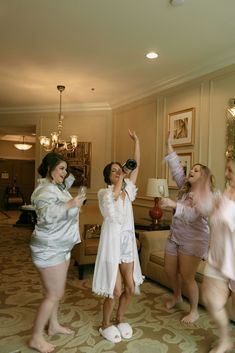 three women in white robes are dancing and having fun