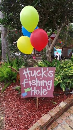 a sign that says tuck's fishing hole in front of some plants and trees