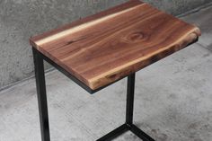 a wooden table sitting on top of a metal stand next to a wall and cement floor