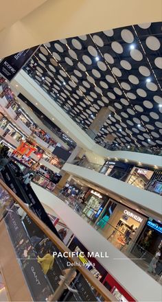 the interior of a shopping mall with lots of shops and people walking through it,