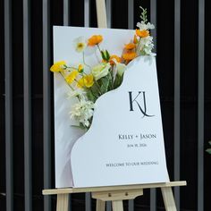 a sign with flowers on it sitting in front of a metal fence and black background