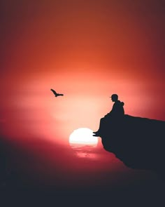 a person standing on top of a cliff with the sun setting in the sky behind them