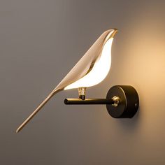 a wall mounted light with a bird on it's arm and a long tail