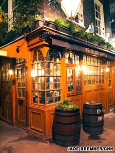 the outside of a pub at night with lights on and plants growing out of it