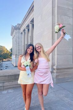 two young women posing for the camera in front of a building with columns and flowers