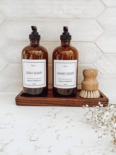 two hand soap bottles sitting on top of a wooden tray