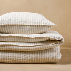 three pillows stacked on top of each other in front of a beige wall and floor