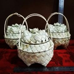 two woven baskets sitting on top of a red tablecloth next to a ruler and measuring tape