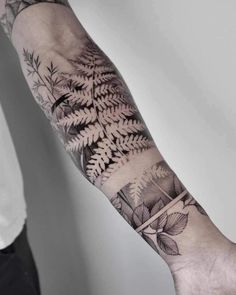 a man's arm with a fern tattoo on it