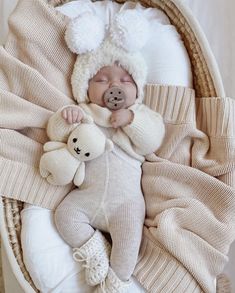 a baby is sleeping in a basket with a teddy bear on it's side