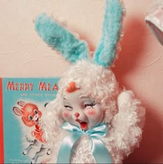 a stuffed bunny with a book on the shelf next to it's ear and nose