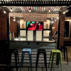 three stools are sitting in front of a bar with lights on the roof and an awning over it