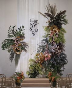 there are many flowers and plants on the wall in front of the ceremony room table