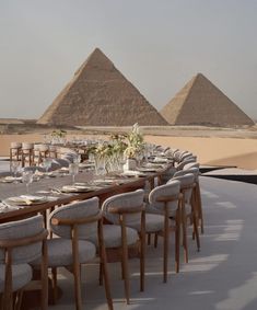 a long table with chairs and plates in front of the pyramids